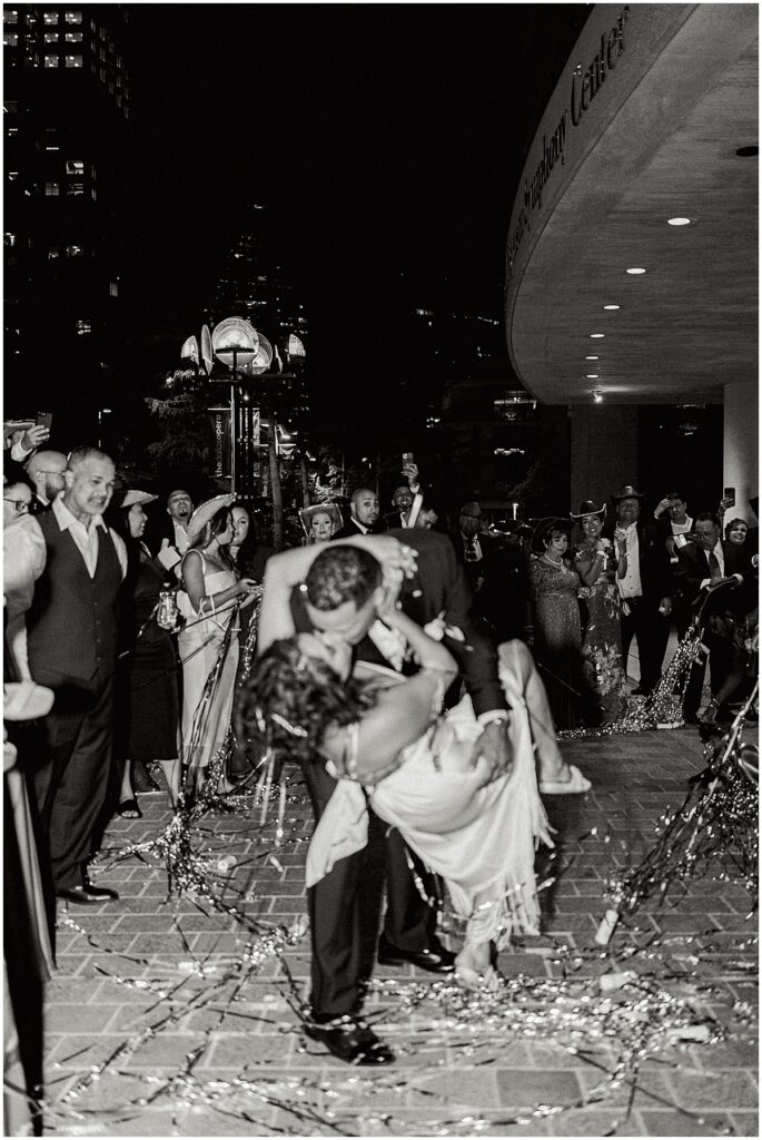 Bride and groom kissing at wedding exit with party poppers at Dallas wedding